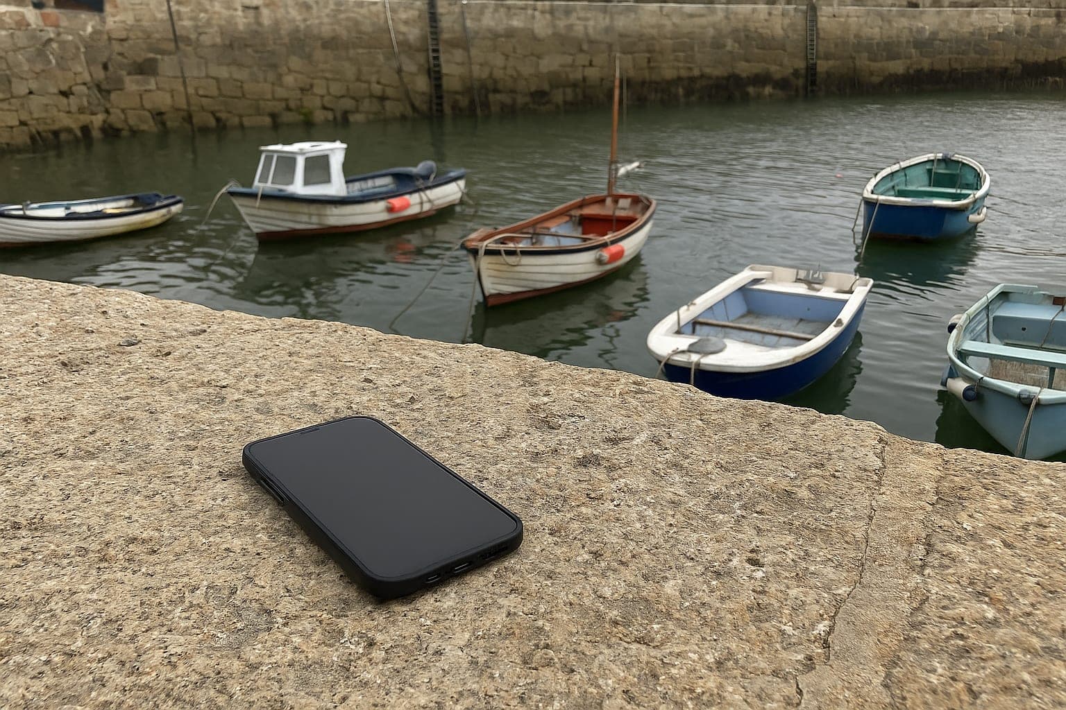 The voucher on the day A phone on a harbour wall with small boats behind